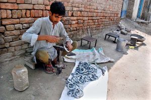 A blacksmith sits by the roadside making Payal and Jhanjhariya for animals