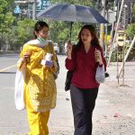 Women on thier way under the cover of an umbrella to protect from sunlight during scorching hot weather in the city