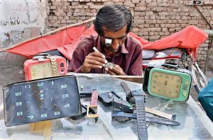 A man repairing clock at his roadside setup near Jinnah Bagh