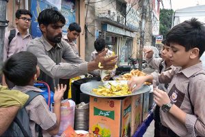 Students purchasing food items from roadside vendor