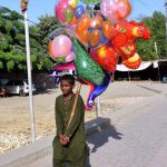A young vendor selling balloons to attract the customers at Al Murtaza House Road