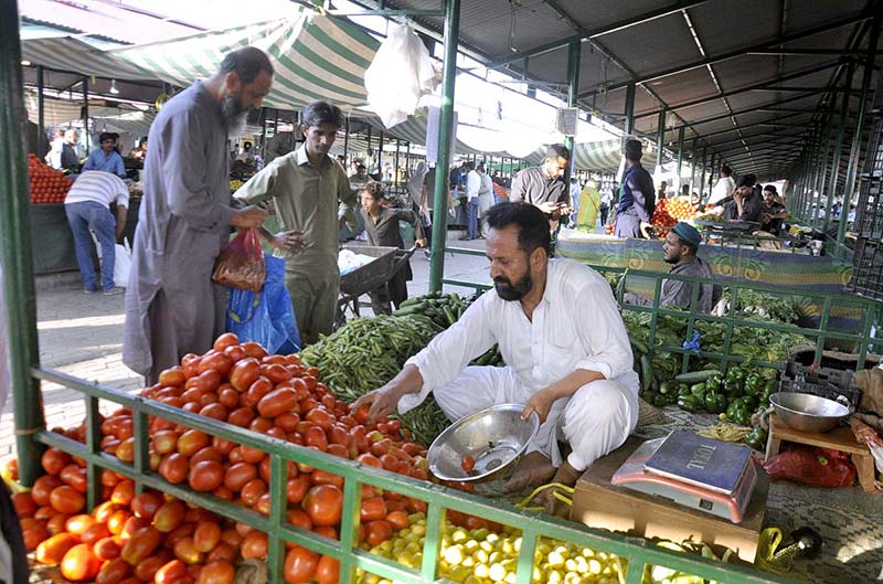 People purchasing fresh vegetables from a stall in H-9 weekly bazar.