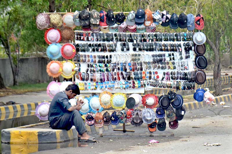 Vendor selling hats and glasses while sitting at his roadside setup