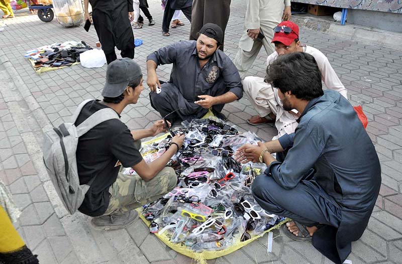 Youngsters selecting sun glasses from a vendor at H-9 weekly bazar