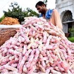 A vendor arranging and displaying the traditional sweet candy to the customers on their handcart at roadside setup.