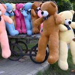 A vendor arranging and displaying Bear toys to attract the customers on their handcart at roadside setup