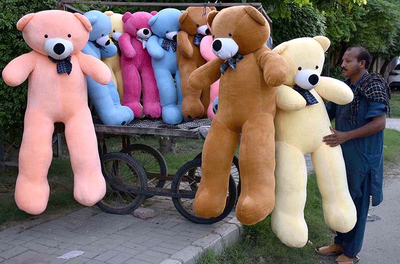 A vendor arranging and displaying Bear toys to attract the customers on their handcart at roadside setup