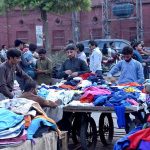 People looking to buy second hand clothes from a cart on the roadside