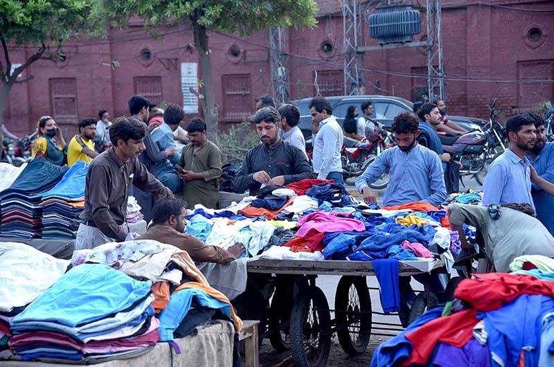 People looking to buy second hand clothes from a cart on the roadside