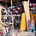 A shopkeeper displays caps to attract the customers.