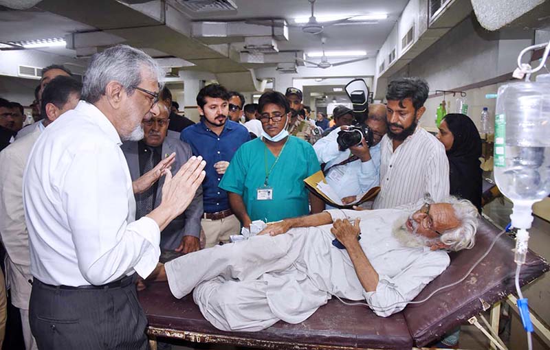 Caretaker Chief Minister Justice (rtd) Maqbool Baqar interacts with a patient during his visit to the Emergency of the Jinnah Postgraduate Medical Center.