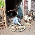Workers busy in repairing donkey cart wheel at his workplace.