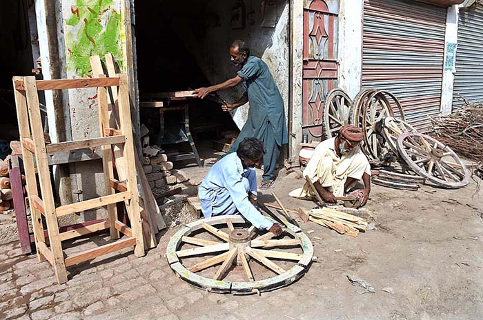 Workers busy in repairing donkey cart wheel at his workplace.