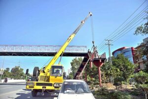 A labourer busy in welding the grills of newly installed pedestrian bridge at IJP Road.