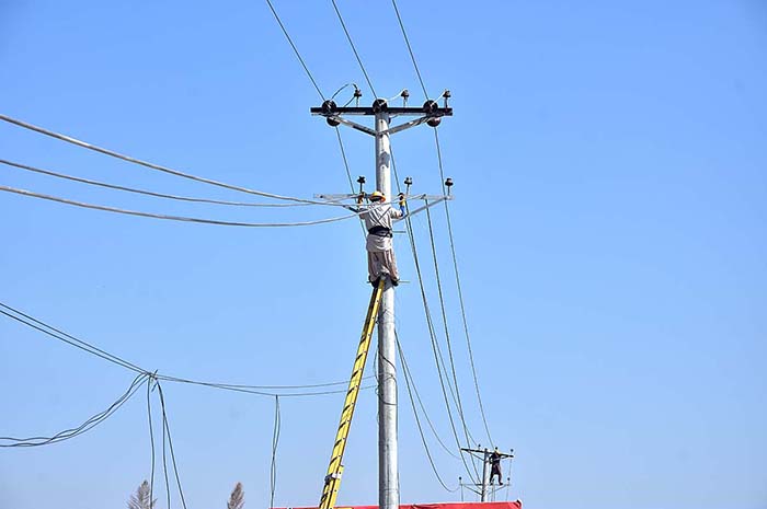 WAPDA staffers busy in installing new electric wires on electric poles at Taramri Chowk.