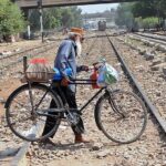 An elderly person along with bicycle crossing rail track while a train approaching on the same track may cause any mishap