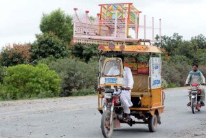  A view of motorcycle rickshaw on the way loaded stuff on rooftop at Naranwala Road. 