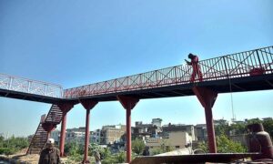 A labourer busy in welding the grills of newly installed pedestrian bridge at IJP Road.