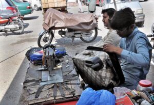A worker repairing old bags at his roadside setup.