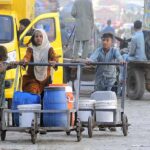 Gypsy children pushing hand carts loaded with water pots after filling from the filtration plant.