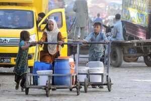 Gypsy children pushing hand carts loaded with water pots after filling from the filtration plant. 