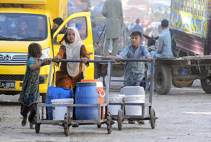 Gypsy children pushing hand carts loaded with water pots after filling from the filtration plant.