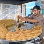 A shopkeeper preparing popular traditional food of Lahoris anda tikki tawa fry to attract the customers at his setup