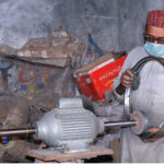 A worker is busy polishing the part of the motorcycle at his workplace