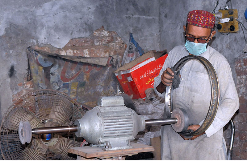 A worker is busy polishing the part of the motorcycle at his workplace