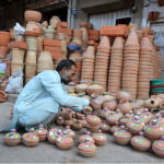 A shopkeeper arranging and displaying clay-made items to attract customers at Dolat Gate