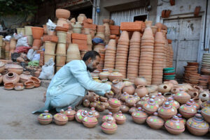A shopkeeper arranging and displaying clay-made items to attract customers at Dolat Gate