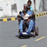A disabled person with his children on the way on his automatic wheelchair towards his destination
