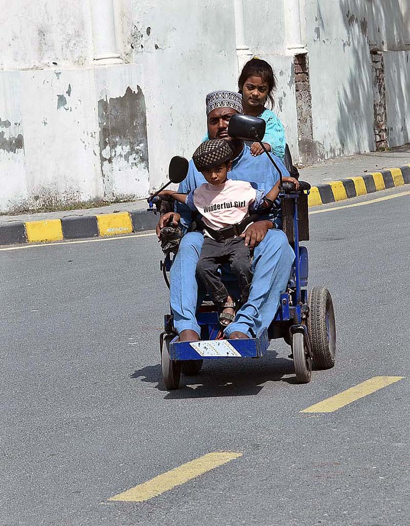 A disabled person with his children on the way on his automatic wheelchair towards his destination