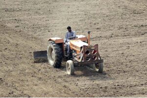 Farmer busy in leveling his farm field with the help of tractor for next crop