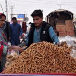 People busy in purchasing traditional sweet item jaggery from a vendor on roadside in the Federal Capital