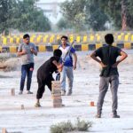 A group of youngsters playing cricket in a local ground.