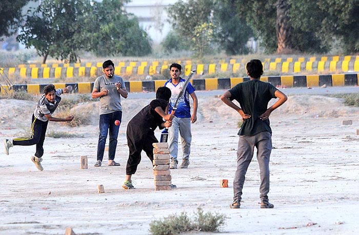 A group of youngsters playing cricket in a local ground.