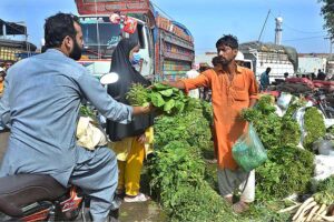 People purchasing spinach from vendor at Vegetable Market