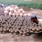 A worker arranging clay-made stuff for drying purpose at his work place in Kumharpara