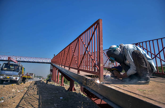 A worker busy fixing pedestrian bridge at Karnal Sher Khan Shaheed Road in the Federal Capital