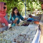Women customers selecting and purchasing stone decoration items from a roadside vendor on GT Road.