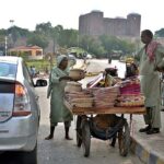 A woman vendor selling traditional handmade items on handcart at roadside.