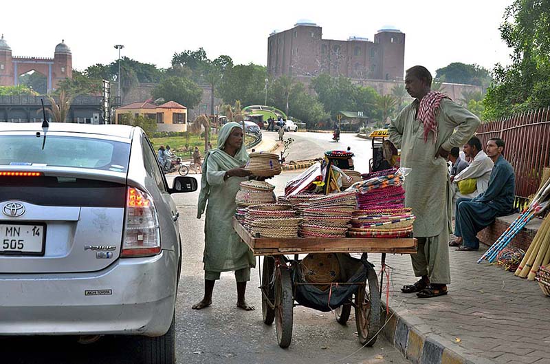 A woman vendor selling traditional handmade items on handcart at roadside.