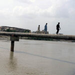 Youngsters crossing the Phuleli Canal in risky way through water pipeline