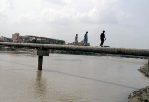 Youngsters crossing the Phuleli Canal in risky way through water pipeline