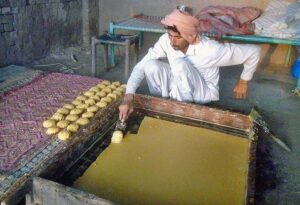 A worker busy in preparing traditional “Gurr” at Lahore Road