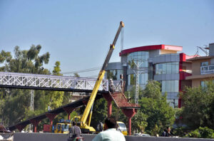 A worker busy fixing pedestrian bridge at Karnal Sher Khan Shaheed Road in the Federal Capital