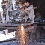 A laborer is busy cutting iron sheet at his work Place.