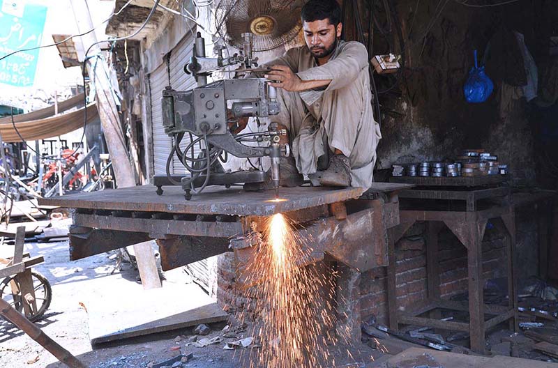 A laborer is busy cutting iron sheet at his work Place.