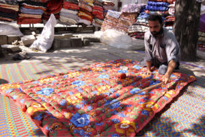 A man is sewing and manually making woven quilt at his work place for upcoming winter as the demand for woolies and quilts